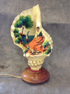 Avdelning: Souvenirer. Beskrivning: Lampa gjord av bemålad snäcka.